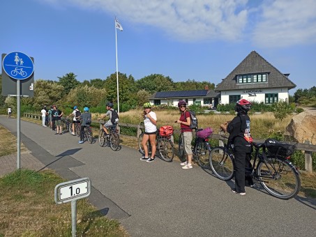 Jugendliche stehen mit Fahrrädern hintereinander am Rand des Fahrradweges.