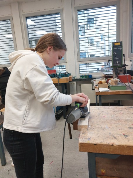 Ein Mädchen arbeitet mit der Schleifmaschine.